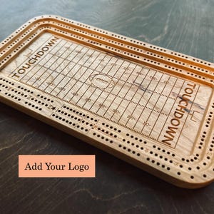 Peut inclure: Jeu de cribbage en bois avec un motif de terrain de football américain. Le plateau rectangulaire aux coins arrondis porte le mot « TOUCHDOWN » et un graphique de terrain de football. Le plateau comporte des trous pour les chevilles.
