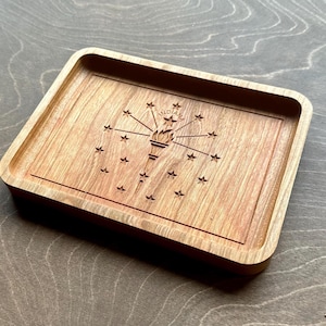 May include: A rectangular wooden tray with rounded corners. The tray features a carved design of the Indiana state flag, including a torch and stars. The wood has a warm, natural tone, and the tray is set against a neutral background.