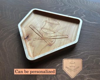 May include: A light-colored wooden baseball-themed tray with a home plate shape. The tray features an engraved baseball and crossed bats design. A smaller, matching home plate-shaped plaque is also visible. The text "Can be personalized" is displayed.