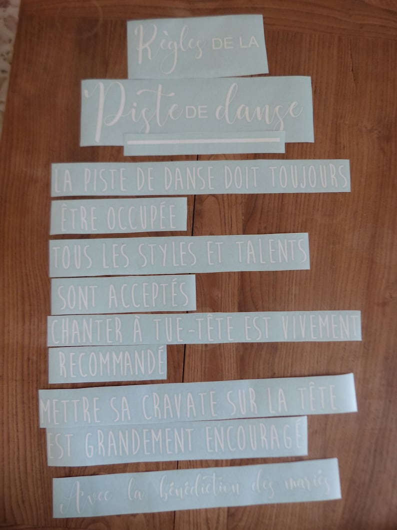 May include: Light blue vinyl stickers with white text that reads "R&egrave;gles de la Piste de danse" and includes rules for a dance floor. The rules are: "La piste de danse doit toujours &ecirc;tre occup&eacute;e", "Tous les styles et talents sont accept&eacute;s", "Chanter &agrave; tue-t&ecirc;te est vivement recommand&eacute;", "Mettre sa cravate sur la t&ecirc;te est grandement encourag&eacute;", and "Avec la b&eacute;n&eacute;diction des mari&eacute;s".