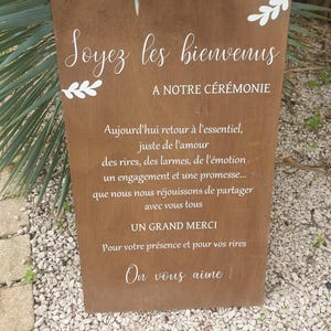 Peut inclure: Une pancarte en bois rustique de couleur marron avec du texte blanc qui dit "Soyez les bienvenus A NOTRE CEREMONIE Aujourd'hui retour à l'essentiel, juste de l'amour des rires, des larmes, de l'émotion un engagement et une promesse... que nous nous réjouissons de partager avec vous tous UN GRAND MERCI Pour votre présence et pour vos rires On vous aime".