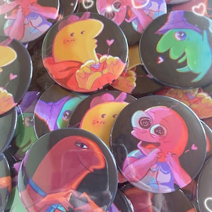 Puede incluir: Una colección de pines de personajes de dibujos animados coloridos con fondos negros. Los pines presentan personajes con diferentes expresiones y poses. Algunos de los personajes llevan sombreros y tienen corazones a su alrededor.