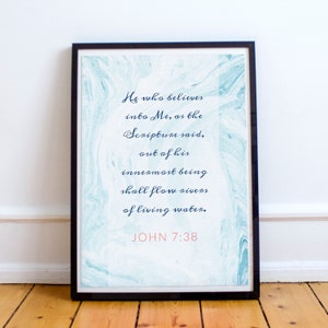 May include: A framed print with a blue and white marbled background. The print features a quote from the Bible, John 7:38, in a dark blue font. The quote reads: "He who believes into Me, as the Scripture said, out of his innermost being shall flow rivers of living water."