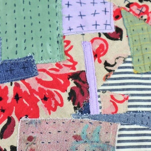 以下が含まれることがあります： デニム、花柄、ストライプ生地など、さまざまな生地で作られたパッチワークキルト。キルトは異なる色の糸で縫い合わせられており、ユニークで質感のあるデザインになっています。