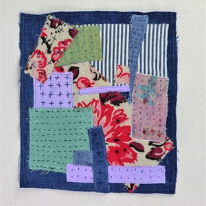 Op de afbeelding: Een patchworkdeken gemaakt van verschillende stoffen, waaronder denim, bloemenprint en gestreept stof. De deken is een mix van blauwe, groene, roze en rode kleuren.