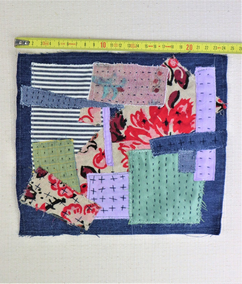 以下が含まれることがあります： デニム、花柄、ストライプなど、さまざまな生地で作られたパッチワークキルト。キルトはさまざまなステッチで縫い合わせられ、濃い青色のデニムの縁取りが施されています。