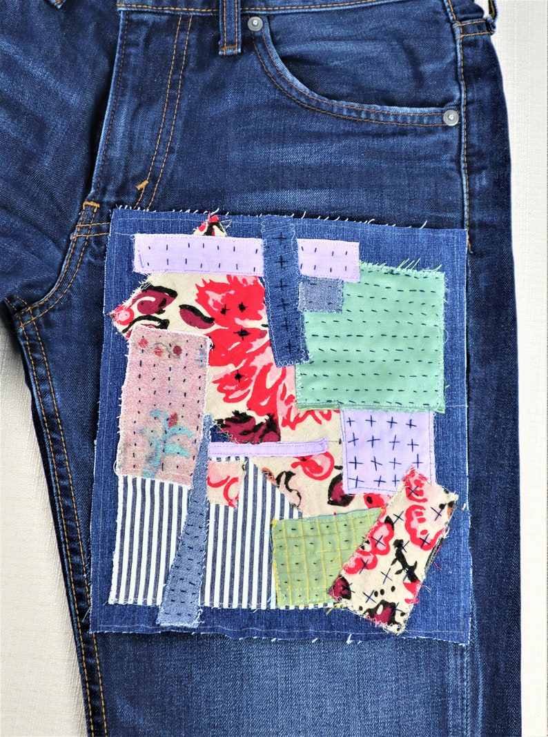 以下が含まれることがあります： 前面のポケットにパッチワークのデザインが施された青いデニムジーンズ。パッチワークは、花柄、ストライプ、チェックなど、さまざまな色のさまざまな生地で構成されています。