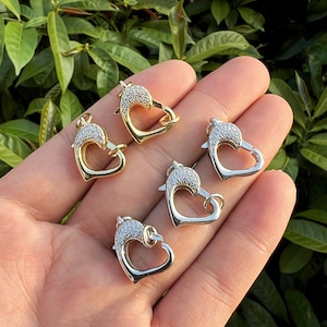 Könnte beinhalten: Vier herzförmige Verschlüsse mit klaren Strasssteinen. Zwei Verschlüsse sind goldfarben und zwei sind silberfarben.