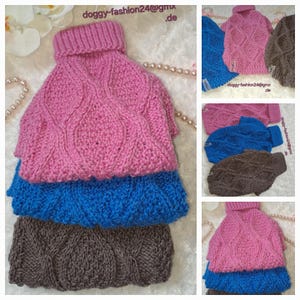 Könnte beinhalten: Drei gestrickte Hunde-Pullover in Pink, Blau und Braun mit einem Zopfmuster. Die Pullover sind übereinander gestapelt.
