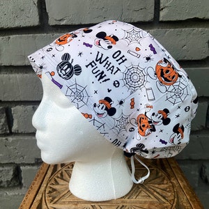 Pode incluir: Um gorro de trabalho branco com um tema de Halloween do Mickey Mouse. O gorro apresenta o Mickey Mouse e abóboras com o texto "Oh What Fun!"