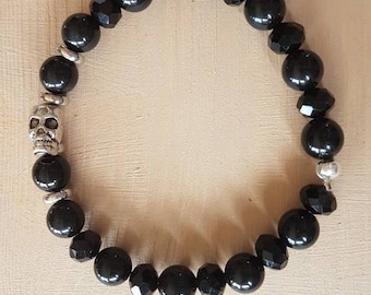 Op de afbeelding: Zwarte kralen armband met een zilveren schedel bedel.