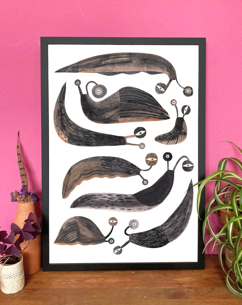 Op de afbeelding: Een zwart ingelijste print van een grillige illustratie van zes gestileerde slakken in tinten bruin en zwart op een witte achtergrond.