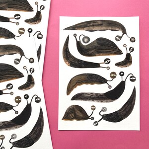 Op de afbeelding: Een witte achtergrond met een zwart-witte illustratie van een groep slakken. De slakken zijn van verschillende groottes en vormen, en ze zijn allemaal in verschillende richtingen gericht. De slakken hebben grote ogen en kleine monden. De illustratie is een grillige en speelse weergave van deze wezens.