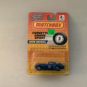 Puede incluir: Un coche de juguete Corvette Grand Sport Matchbox azul de metal fundido a presión en su embalaje original naranja y amarillo. El embalaje incluye el logotipo de Matchbox y el número "15" en el coche.