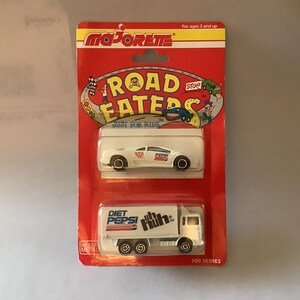 May include: A Majorette Road Eaters toy set featuring a white sports car and a Diet Pepsi truck. The packaging is red and yellow with the text "Road Eaters" and "Just for Kids".