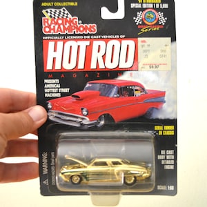 Könnte beinhalten: Ein goldenes Druckgussmodell eines '51 Studebaker in der Originalverpackung. Die Verpackung zeigt das Logo "Racing Champions" und das Branding "Hot Rod Magazine" mit einer roten Autografik. Maßstab 1:60.