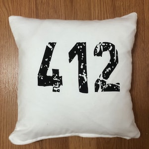 May include: White pillow with black distressed lettering that reads "412".