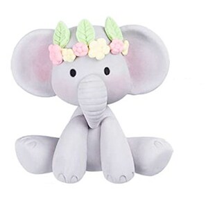 Puede incluir: Una figurita de elefante gris que lleva una corona de flores con flores rosas, amarillas y verdes. El elefante est&aacute; sentado con las piernas cruzadas y tiene una expresi&oacute;n dulce en su rostro.