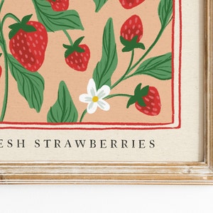 Pu&ograve; includere: Stampa incorniciata con un'illustrazione di fragole. L'opera presenta fragole rosse, foglie verdi e fiori bianchi su uno sfondo color pesca. Il testo "FRESH STRAWBERRIES" &egrave; in basso, all'interno di un bordo rosso.