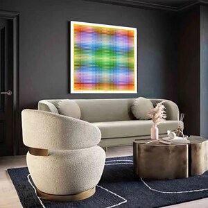 May include: A white, fluffy armchair with a gold metal base sits in a living room with a gray sofa, a coffee table, and a colorful abstract artwork on the wall.