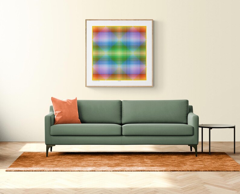 May include: A green sofa with a burnt orange throw pillow sits in front of a framed abstract art print with a yellow, green, blue, and purple color scheme. The sofa is in front of a brown rug on a wood floor.