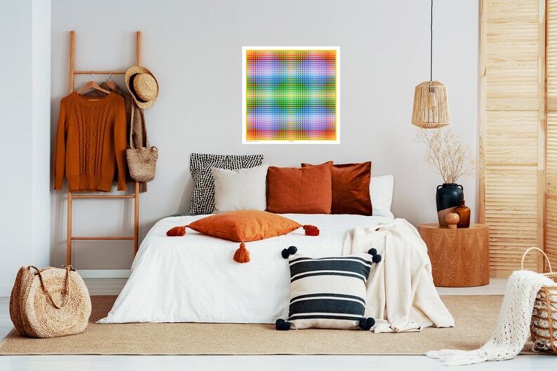 May include: A bedroom interior with a white bed, a brown rug, and a colorful abstract artwork hanging on the wall. The bed is made with white bedding and has several pillows in various colors and patterns. There is a wooden side table with a vase of dried flowers and a brown wicker basket on the floor.