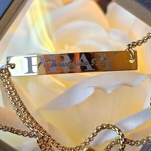 May include: Gold bracelet with a sliding clasp and a rectangular charm that reads "Pray Thessalonians 5:17".