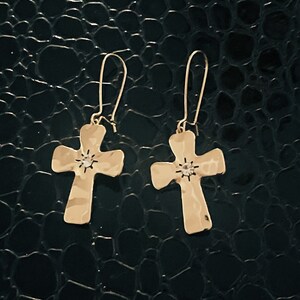 May include: A pair of gold cross earrings with a small clear rhinestone in the center of each cross.