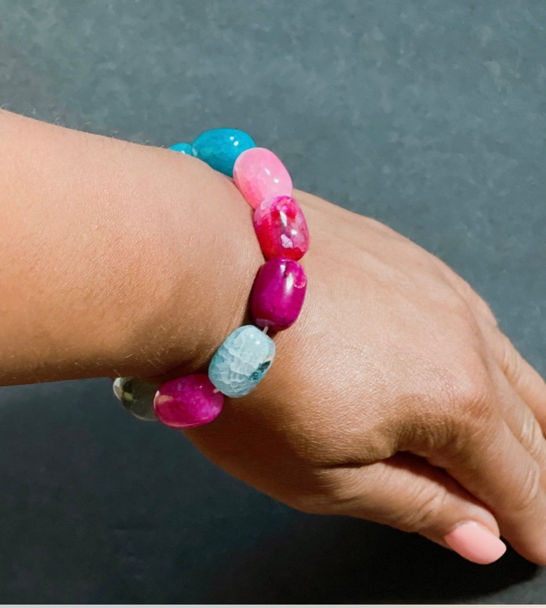 Pu&ograve; includere: Un braccialetto di perline di agata colorate con perline rosa, blu e bianche. Il braccialetto &egrave; realizzato con pietre naturali e ha un aspetto unico e organico.