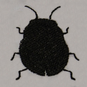 May include: Black embroidered silhouette of a beetle on a white fabric background.