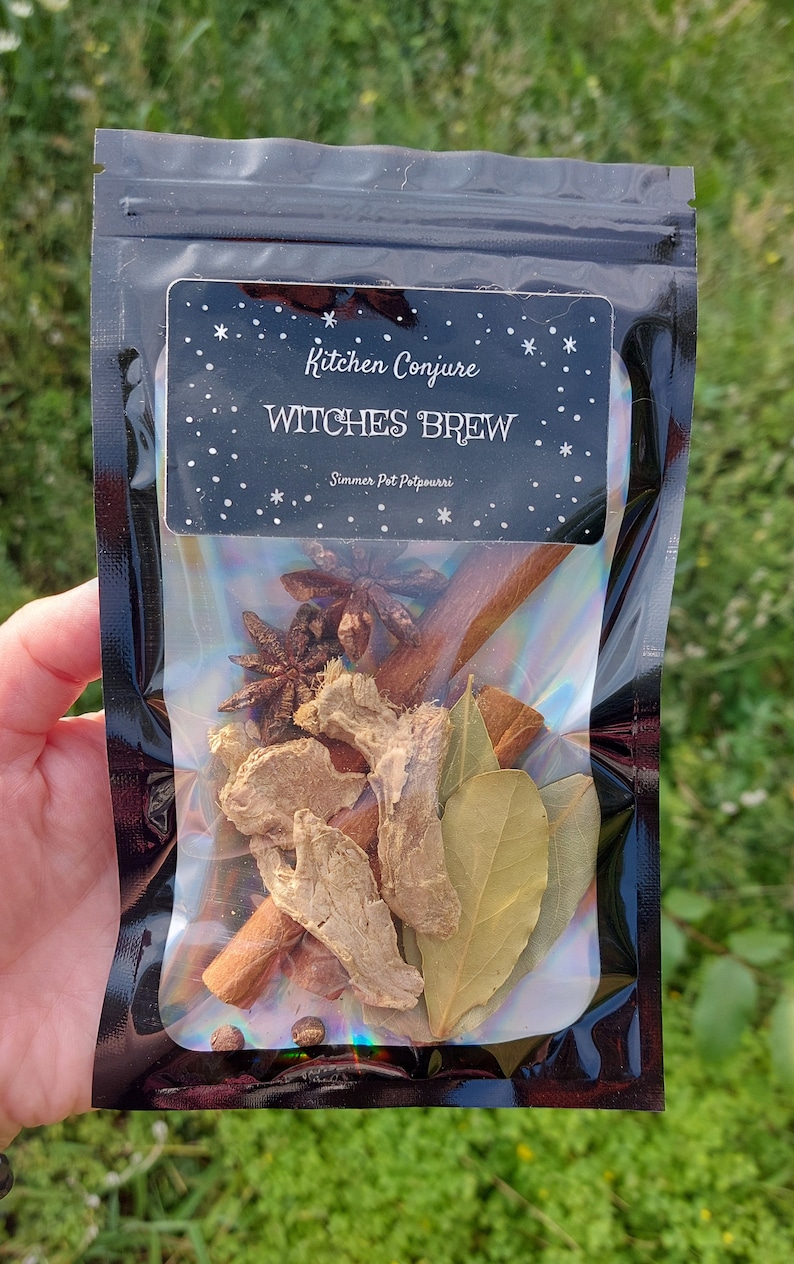 Może przedstawiać: Czarny woreczek z przezroczystym okienkiem, w kt&oacute;rym widać mieszankę przypraw i zi&oacute;ł do gotowania w garnku. Etykieta głosi "Kitchen Conjure Witches Brew Simmer Pot Potpourri".