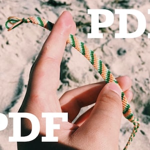 May include: A close-up of a hand holding a multi-coloured friendship bracelet with green, orange and white stripes. The bracelet is tied with a knot at one end. The word "PDF" is written in white letters on a sandy background.