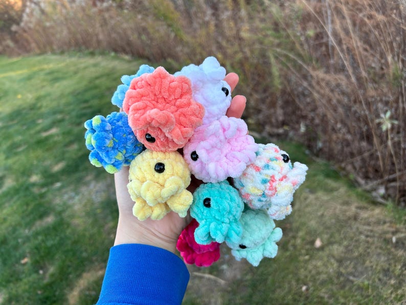 May include: A collection of colorful crocheted plush toys in various shapes and sizes. The toys are made of soft, fuzzy yarn and have black eyes.