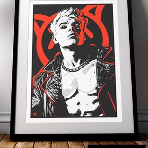 May include: Framed art print depicting a stylized illustration of a person in a leather jacket and chain necklace. The artwork uses black, white, and red, with a striking graphic design. The print is presented in a black frame.