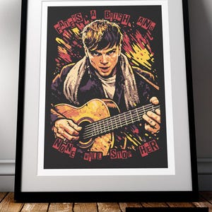 May include: Framed art print of a man playing a guitar, with the text "Fate's a Bitch and None Will Stop Her". The artwork is in a black frame and has a vintage, distressed style, suitable for wall decor.