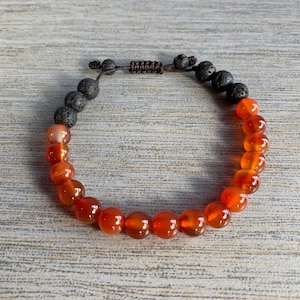 Op de afbeelding: Een armband gemaakt van carneol en lavasteen kralen. De armband is bruin en oranje.