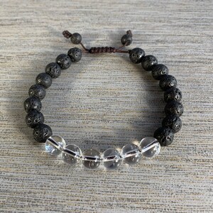 Puede incluir: Pulsera de cuentas de lava negra y cristal transparente con cierre de cordón marrón.