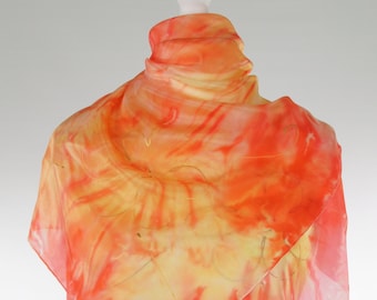 Może przedstawiać: Jedwabna chusta z wzorem tie-dye w odcieniach pomarańczowego, żółtego i różowego. Chusta jest udrapowana na białym manekinie.