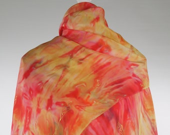 Może przedstawiać: Czerwono-żółty jedwabny szal z wzorem tie-dye. Szal jest drapowany na białym manekinie.