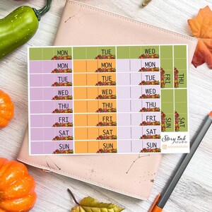 May include: A weekly planner sticker sheet with floral accents and days of the week labels. The sheet is on a pink surface with pumpkins and leaves. The design includes sections for each day of the week. The text "Story Ink Studio" is visible.