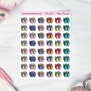 May include: A sheet of colourful gift box stickers with a white background. The stickers feature a variety of colours, including pink, blue, green, yellow, and orange. The text "Story Ink Studio" and "Mini Presents" is printed at the top of the sheet.