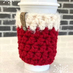 May include: Red and white crocheted coffee cup cozy with a brown leather tag that says "Tangled".