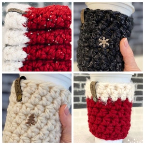 May include: Four crocheted coffee cup cozies in different colors and patterns. The cozies are made with a textured stitch and have a brown leather tag with the word "Cozy" written on it.