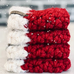 May include: A stack of five red and white crocheted Christmas stocking ornaments with a brown leather tag that says "Family".