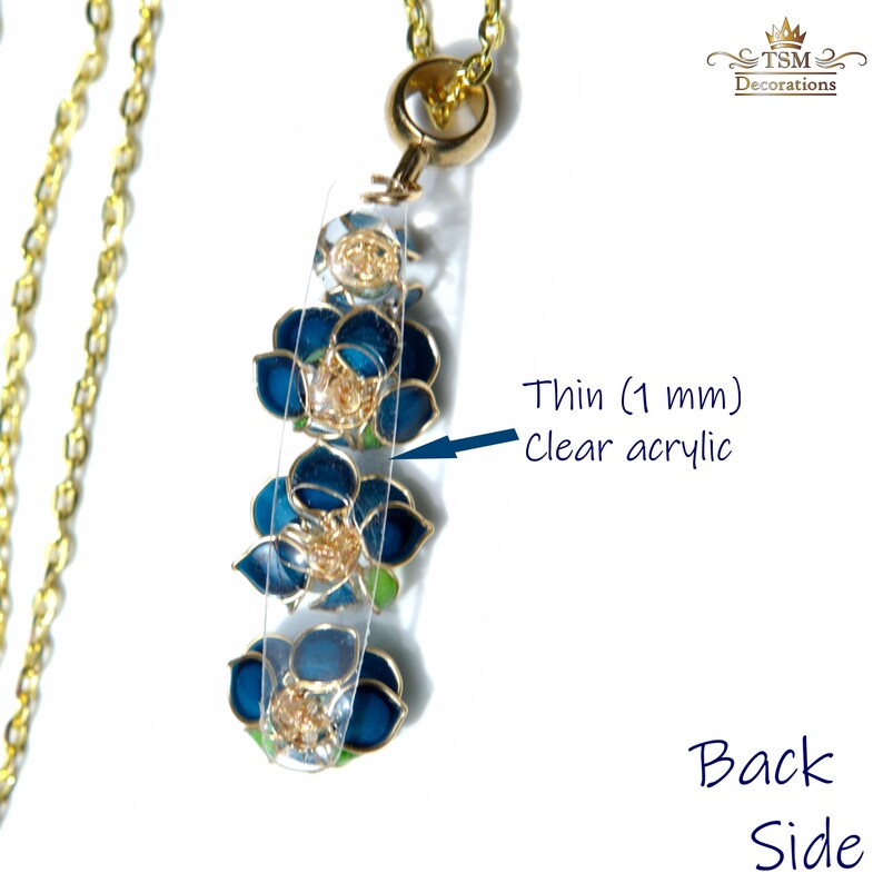 May include: A gold-colored chain necklace with a pendant featuring three blue flower designs on a clear acrylic base. The pendant is thin, measuring 1 mm. The necklace has a gold clasp and a decorative element at the top.