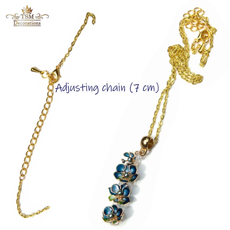 May include: Gold-toned necklace with a pendant of blue and green floral designs. The necklace includes an adjusting chain, approximately 2.75 inches long, and a clasp. The image also shows the brand logo "TSM Decorations".