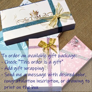 K&ouml;nnte beinhalten: Rechteckige Geschenkboxen in Wei&szlig;, Hellblau und Rosa, jeweils mit glitzerndem Band, goldener Schleife und TSM-Logo. Auf dem Bild sind Anweisungen zum Bestellen eines Geschenkpakets sowie Optionen f&uuml;r die Geschenkverpackung aufgedruckt.