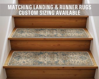 Op de afbeelding: Een set beige en blauwe getrapte treden met een witte rand. De treden zijn op een houten trap. De tekst "Matching Landing & Runner Rugs Custom Sizing Available" staat bovenaan de afbeelding.