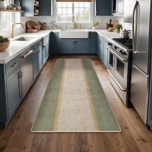 May include: A long rectangular runner rug featuring a wide central beige panel flanked by two sage green side sections. The rug has a thin gold-toned border separating the green and beige areas, with a finished edge binding around the entire perimeter.