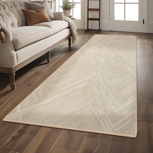 May include: A beige and white runner rug with a geometric pattern. The rug has a subtle sheen and a cream-coloured border.
